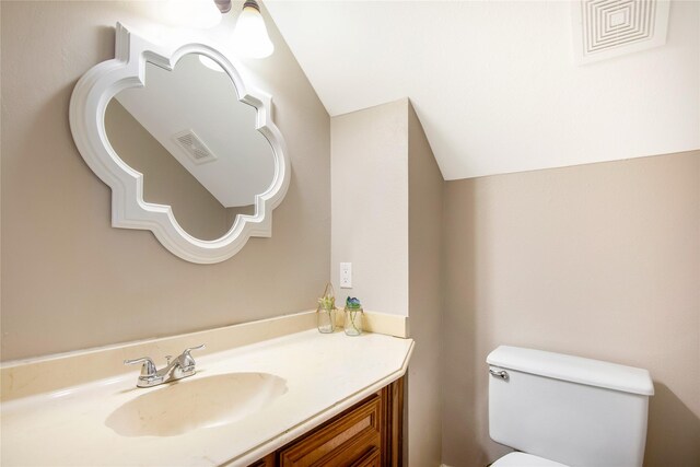 bathroom featuring vanity, toilet, and lofted ceiling