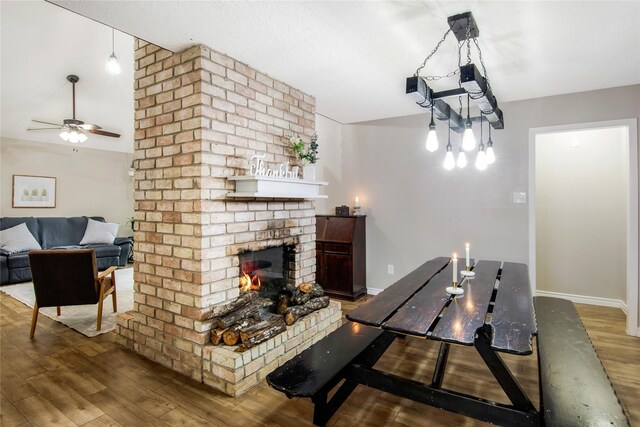 dining area featuring hardwood / wood-style floors, a brick fireplace, and ceiling fan