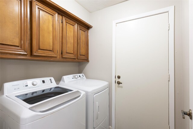 washroom featuring cabinets and washing machine and clothes dryer