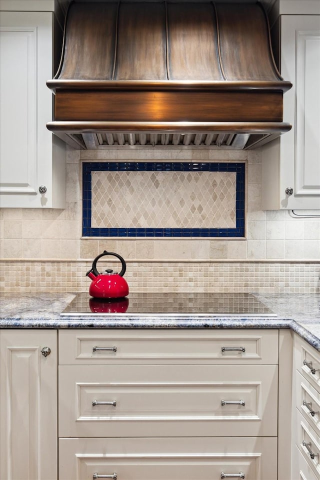 kitchen with decorative backsplash, white cabinets, light stone countertops, and custom exhaust hood