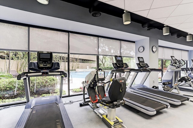 gym with a drop ceiling and a healthy amount of sunlight