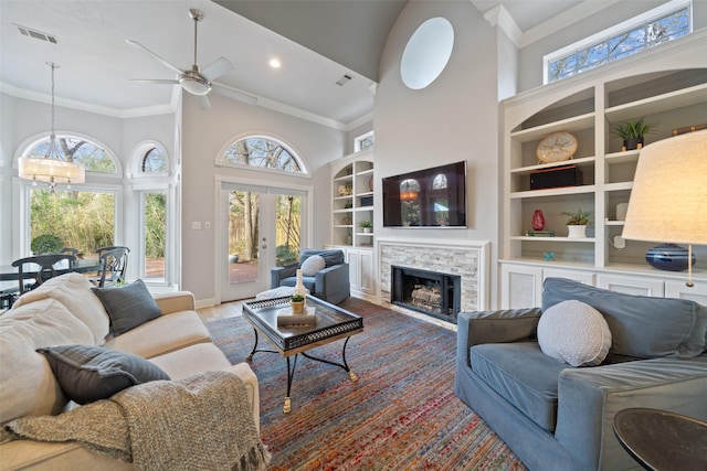 living room with crown molding, built in features, hardwood / wood-style floors, high vaulted ceiling, and french doors