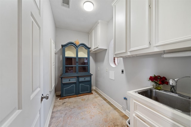 washroom with cabinets, sink, hookup for an electric dryer, and a textured ceiling