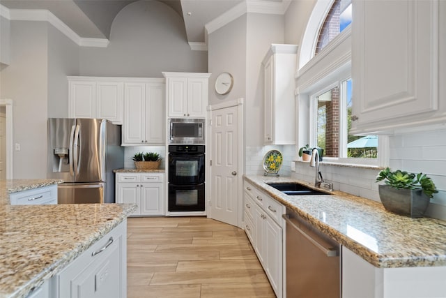 kitchen featuring white cabinetry, stainless steel appliances, sink, and light stone counters