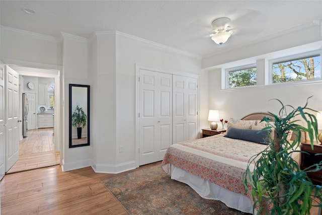 bedroom featuring crown molding, wood-type flooring, stainless steel fridge, and a closet