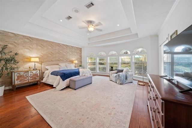 bedroom with a raised ceiling, ornamental molding, dark hardwood / wood-style floors, and ceiling fan