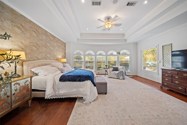 bedroom with dark wood-type flooring, ceiling fan, ornamental molding, and a tray ceiling