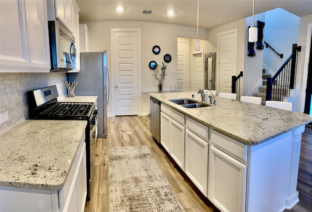 kitchen with white cabinetry, sink, hanging light fixtures, a kitchen island with sink, and appliances with stainless steel finishes