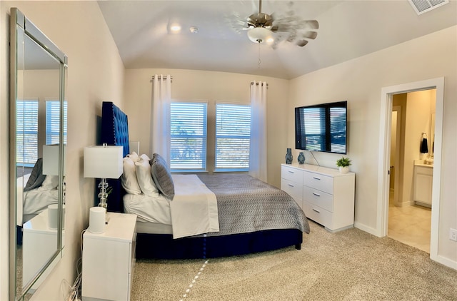 bedroom featuring ceiling fan, ensuite bathroom, light carpet, and vaulted ceiling