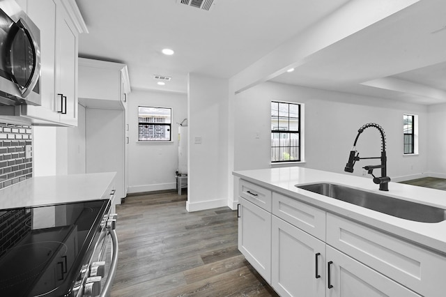 kitchen featuring backsplash, dark wood-type flooring, sink, white cabinetry, and stainless steel appliances