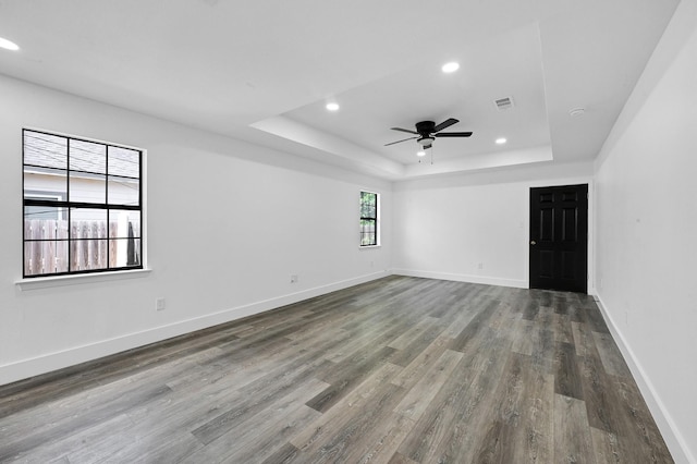 unfurnished room featuring a tray ceiling, ceiling fan, and hardwood / wood-style flooring