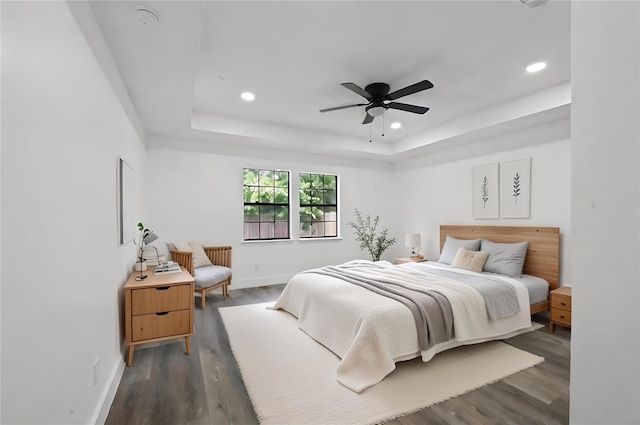 bedroom featuring ceiling fan, a raised ceiling, and dark wood-type flooring