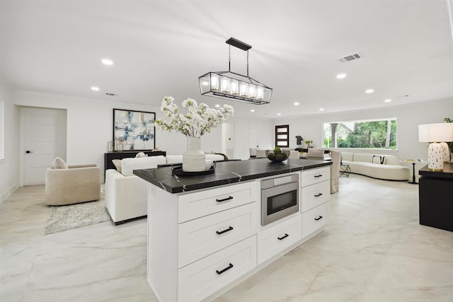 kitchen with white cabinets, built in microwave, a kitchen island, and hanging light fixtures