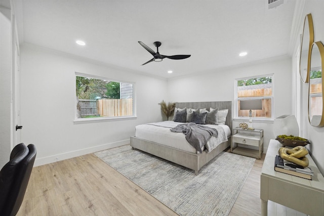 bedroom featuring multiple windows, ceiling fan, crown molding, and light wood-type flooring