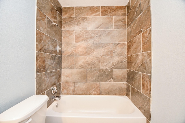 bathroom featuring toilet and tiled shower / bath