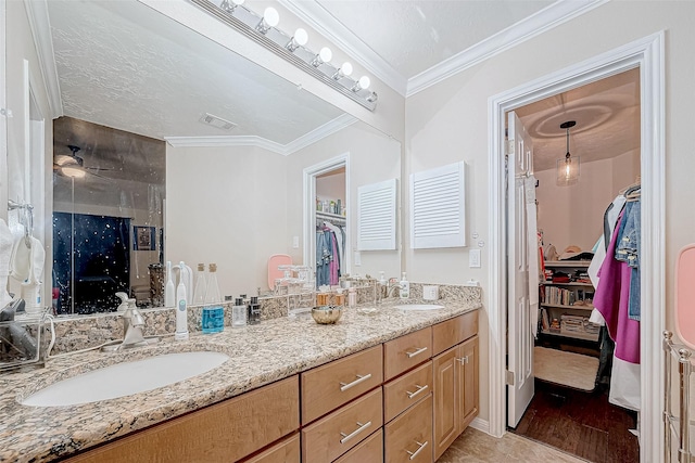 bathroom with vanity, ceiling fan, ornamental molding, and a textured ceiling