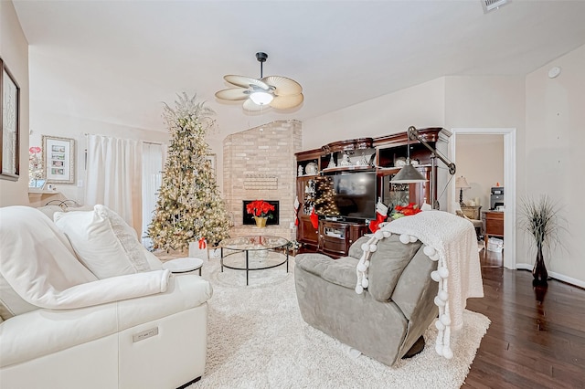 living room featuring a stone fireplace, ceiling fan, and dark wood-type flooring