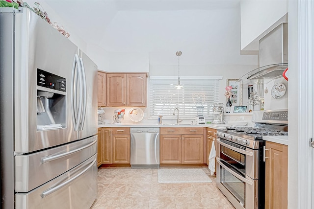 kitchen featuring stainless steel appliances, exhaust hood, sink, light brown cabinets, and hanging light fixtures