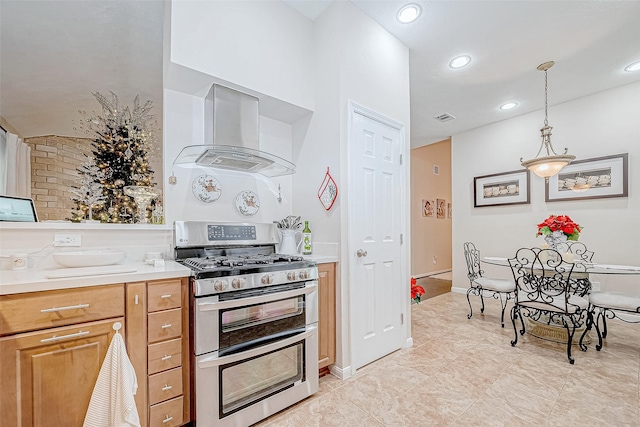 kitchen featuring gas stove, hanging light fixtures, and exhaust hood