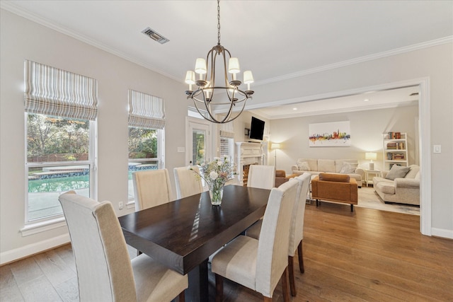 dining room with a notable chandelier, wood-type flooring, crown molding, and a wealth of natural light