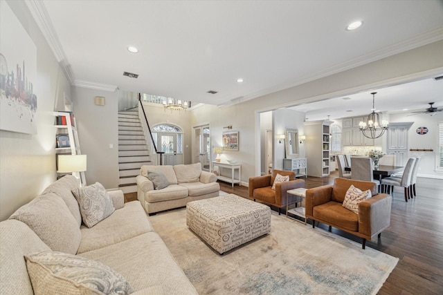 living room with hardwood / wood-style flooring, ceiling fan with notable chandelier, ornamental molding, and a wealth of natural light