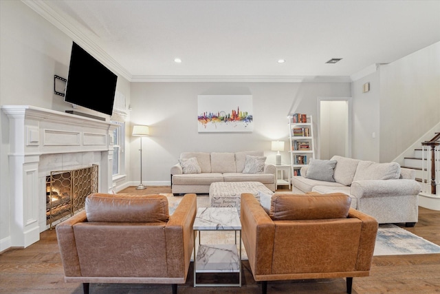 living room with wood-type flooring, ornamental molding, and a tile fireplace