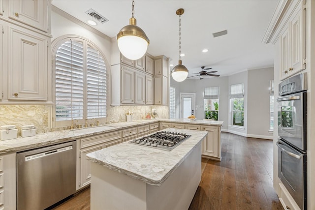 kitchen with decorative light fixtures, a center island, sink, and stainless steel appliances