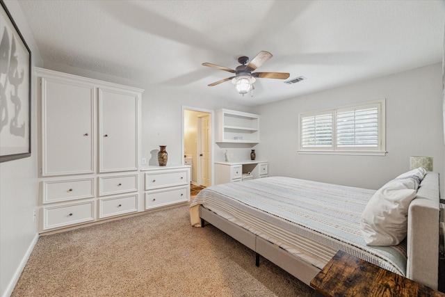 carpeted bedroom with ensuite bath and ceiling fan