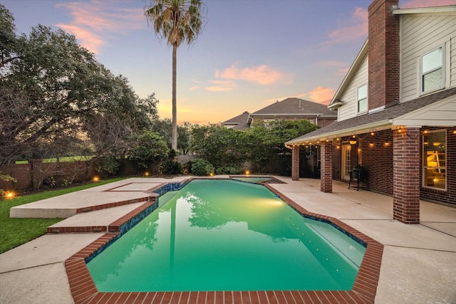 pool at dusk with a patio area