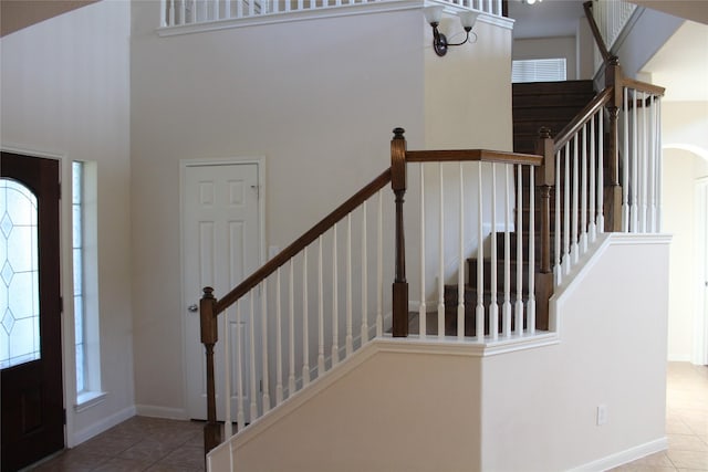 foyer entrance featuring tile patterned floors and a towering ceiling