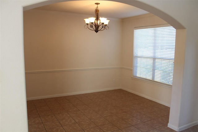 unfurnished room with crown molding, dark tile patterned floors, and a chandelier