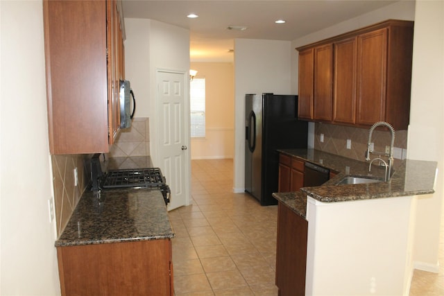 kitchen featuring kitchen peninsula, dark stone counters, black appliances, sink, and light tile patterned floors