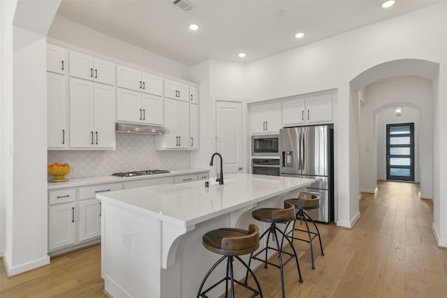 kitchen with a center island with sink, white cabinets, and stainless steel appliances