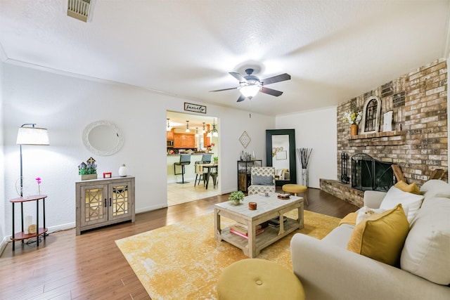 living room with a textured ceiling, ceiling fan, wood-type flooring, and a fireplace