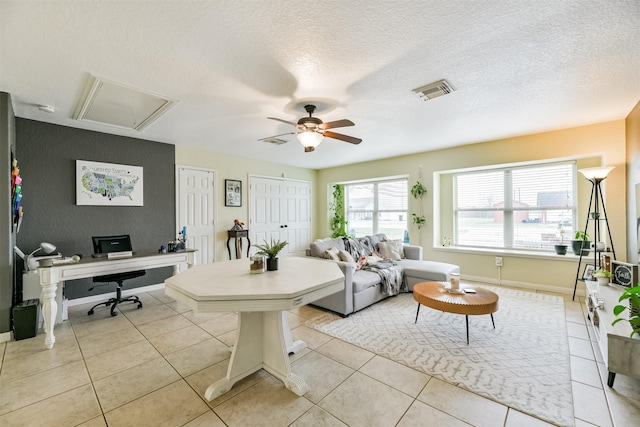 tiled living room with ceiling fan and a textured ceiling