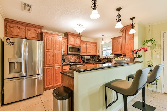 kitchen featuring appliances with stainless steel finishes, crown molding, sink, light tile patterned floors, and pendant lighting