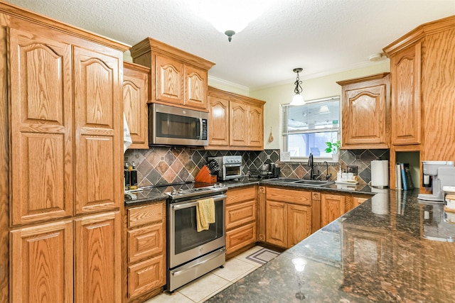 kitchen with tasteful backsplash, stainless steel appliances, sink, pendant lighting, and light tile patterned floors