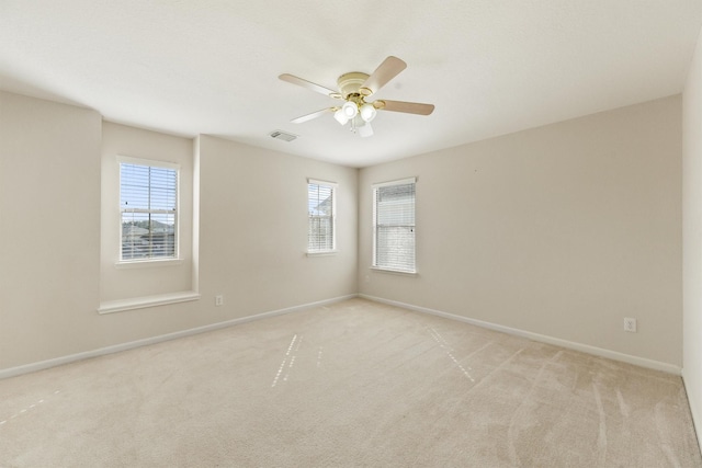 spare room featuring light colored carpet, ceiling fan, and a healthy amount of sunlight