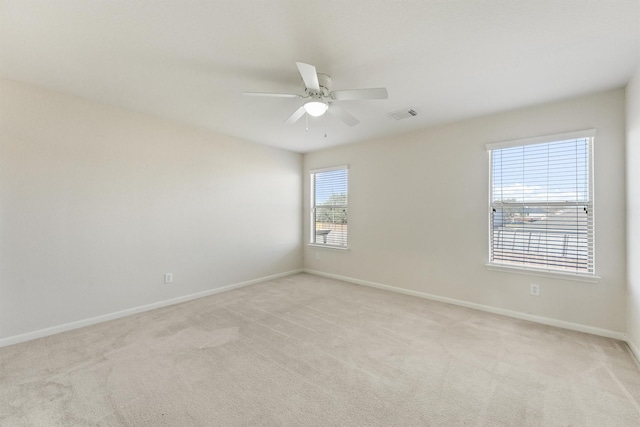 carpeted spare room with a wealth of natural light and ceiling fan