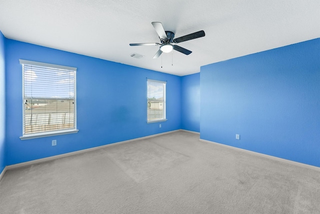 empty room with ceiling fan, light colored carpet, and a healthy amount of sunlight