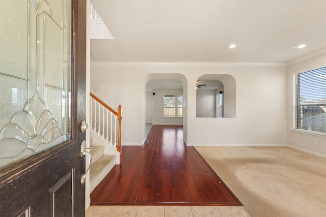 carpeted foyer entrance with ceiling fan and crown molding