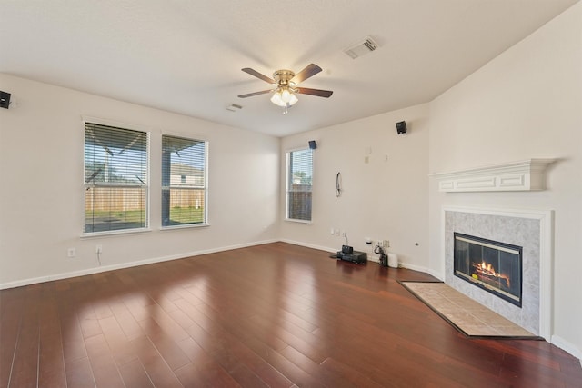 unfurnished living room with a tile fireplace, dark hardwood / wood-style floors, and ceiling fan