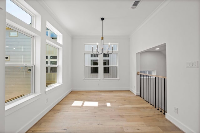 unfurnished dining area with a notable chandelier, a healthy amount of sunlight, crown molding, and light hardwood / wood-style flooring