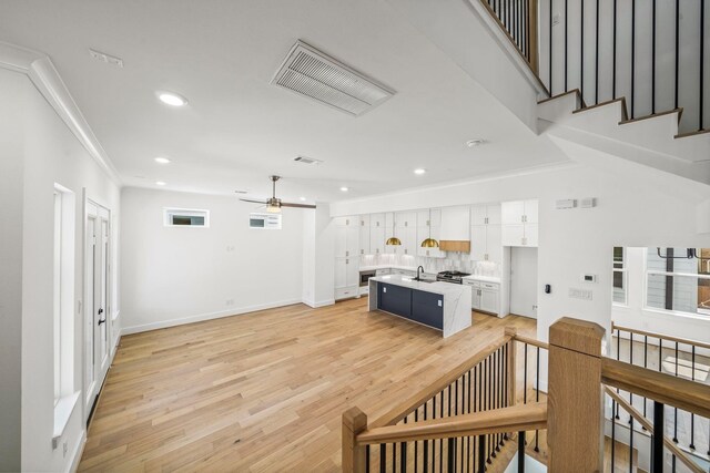 interior space featuring ceiling fan, sink, wood-type flooring, and ornamental molding