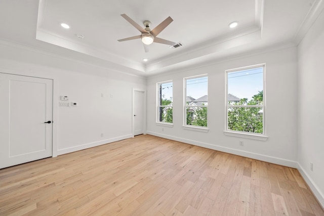 spare room with crown molding, a tray ceiling, light hardwood / wood-style floors, and ceiling fan