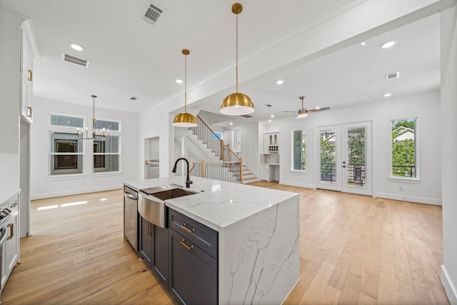 kitchen featuring white cabinetry, an island with sink, light stone counters, and decorative light fixtures