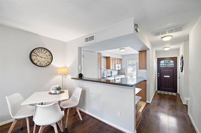 kitchen with dark hardwood / wood-style floors, white appliances, kitchen peninsula, and sink