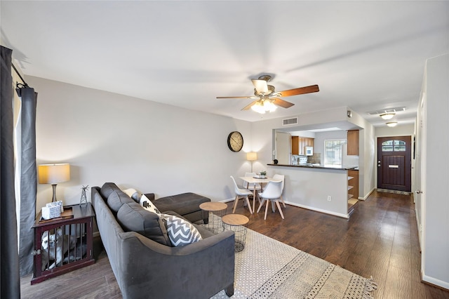 living room with dark hardwood / wood-style flooring and ceiling fan