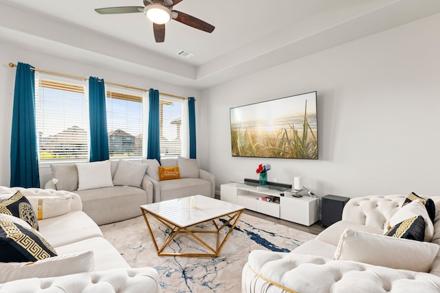 living room with ceiling fan and a tray ceiling