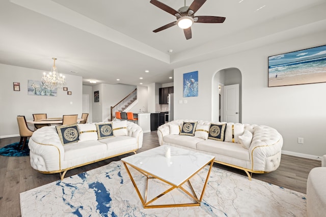 living room with ceiling fan with notable chandelier and hardwood / wood-style floors